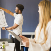Architect showing blueprint to colleague in office