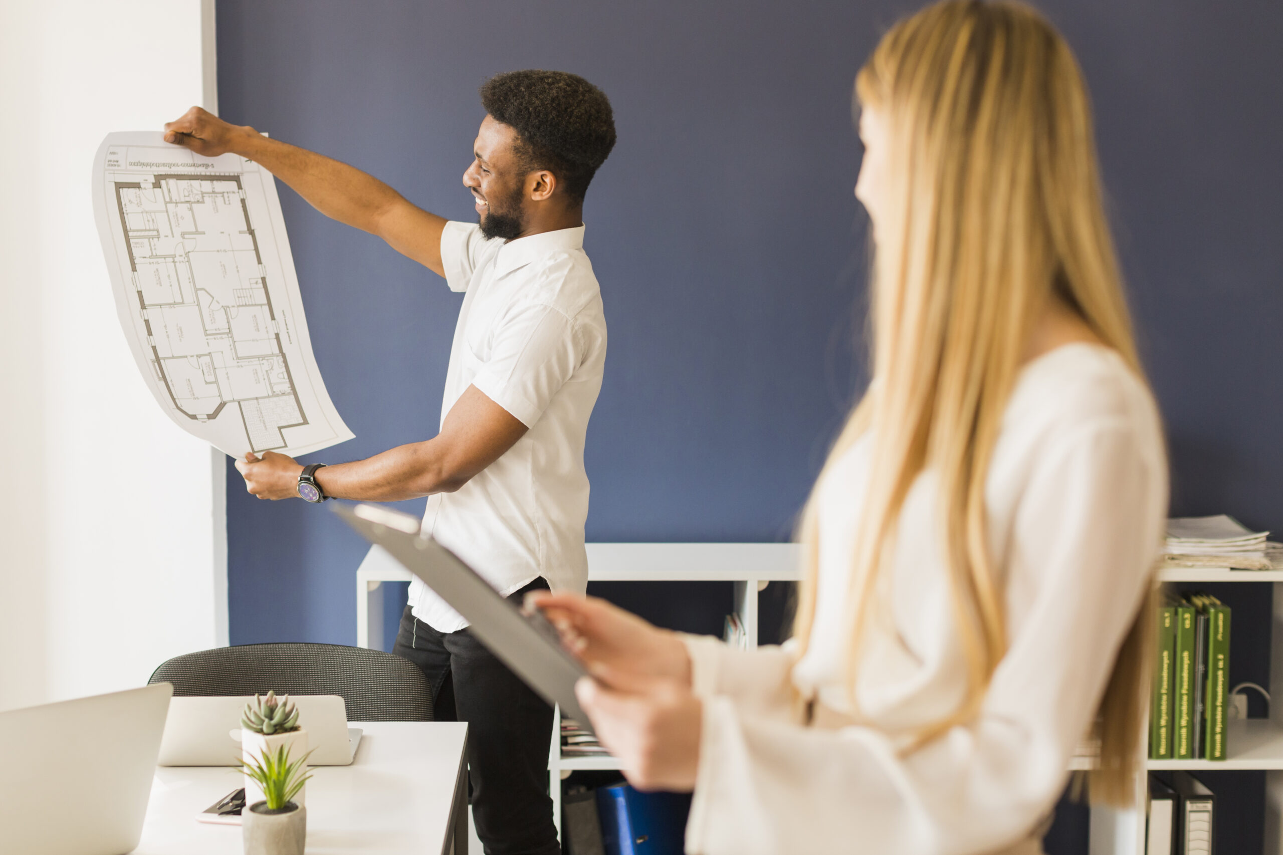 Architect showing blueprint to colleague in office