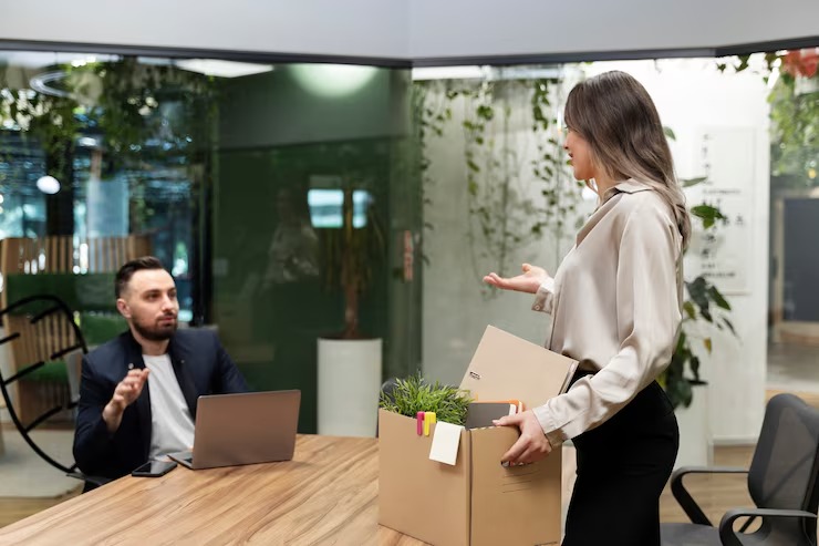 Woman quitting her job and carrying her belongings in a box.