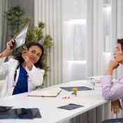 Female doctor in a white coat explaining an X-ray or radiography to a patient in a modern medical office.