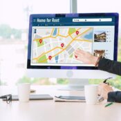 Desktop computer screen displaying an online commercial property search map with rental listings in a modern office meeting